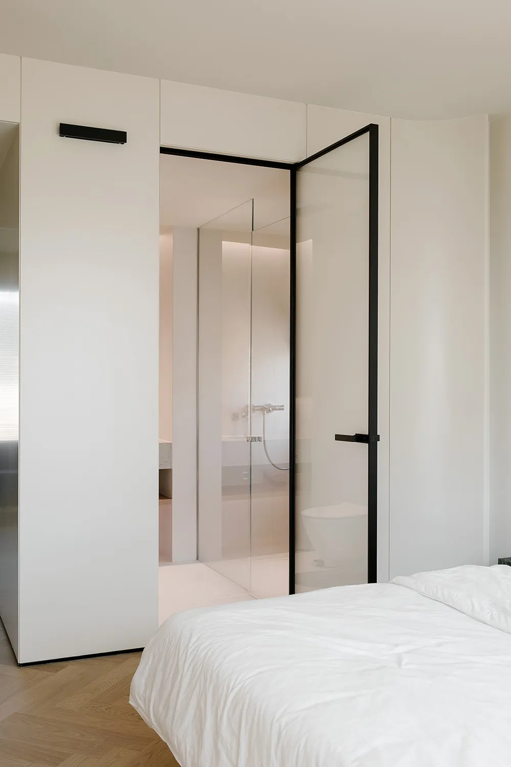 Modern bedroom with a glass door, white walls, and minimalist design.