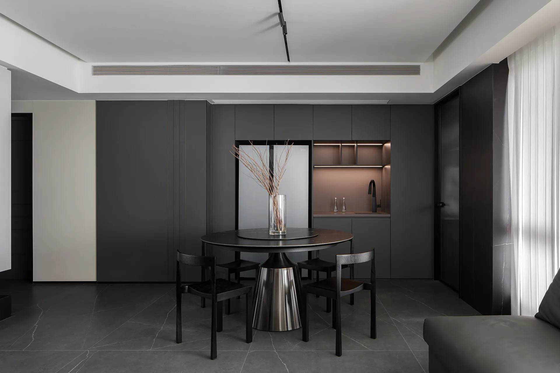 Modern, minimalist kitchen featuring a sleek black metal round table with chairs.