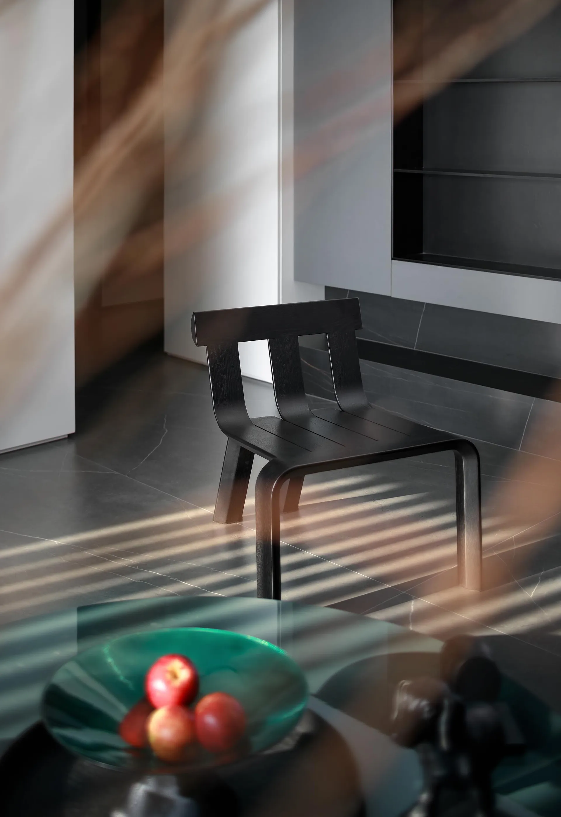 A modern minimalist interior featuring a black wooden chair with a sleek, curved design.