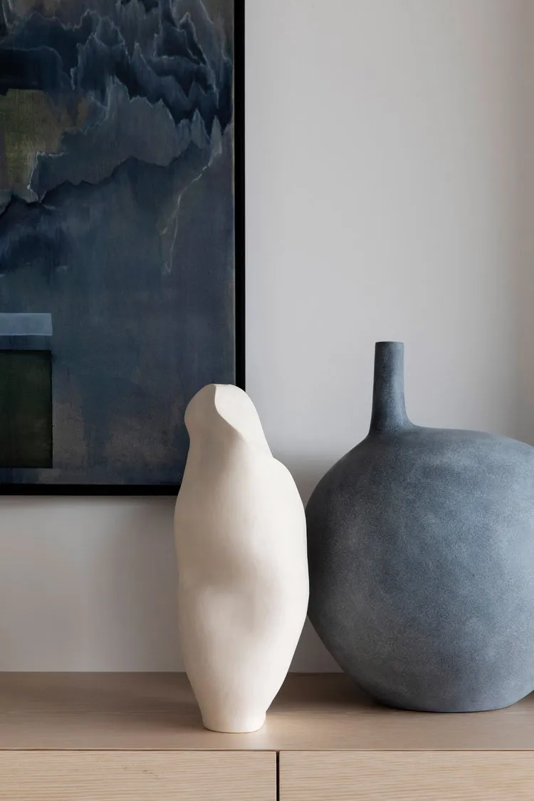 Two ceramic vases with abstract shapes placed on a wooden surface.
