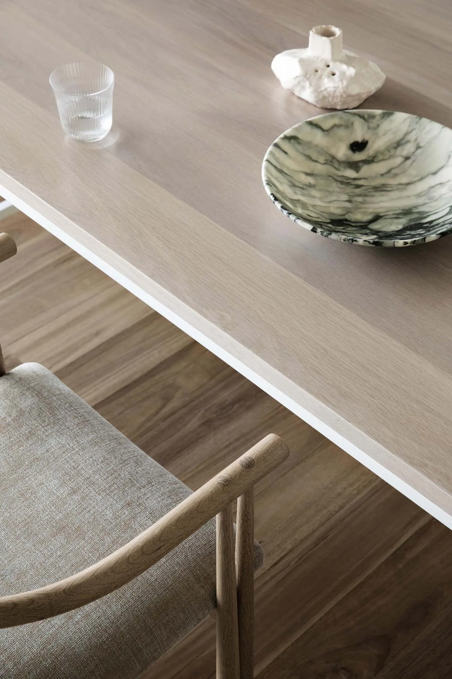 Modern dining room featuring a wooden table with a vase and a marble bowl.