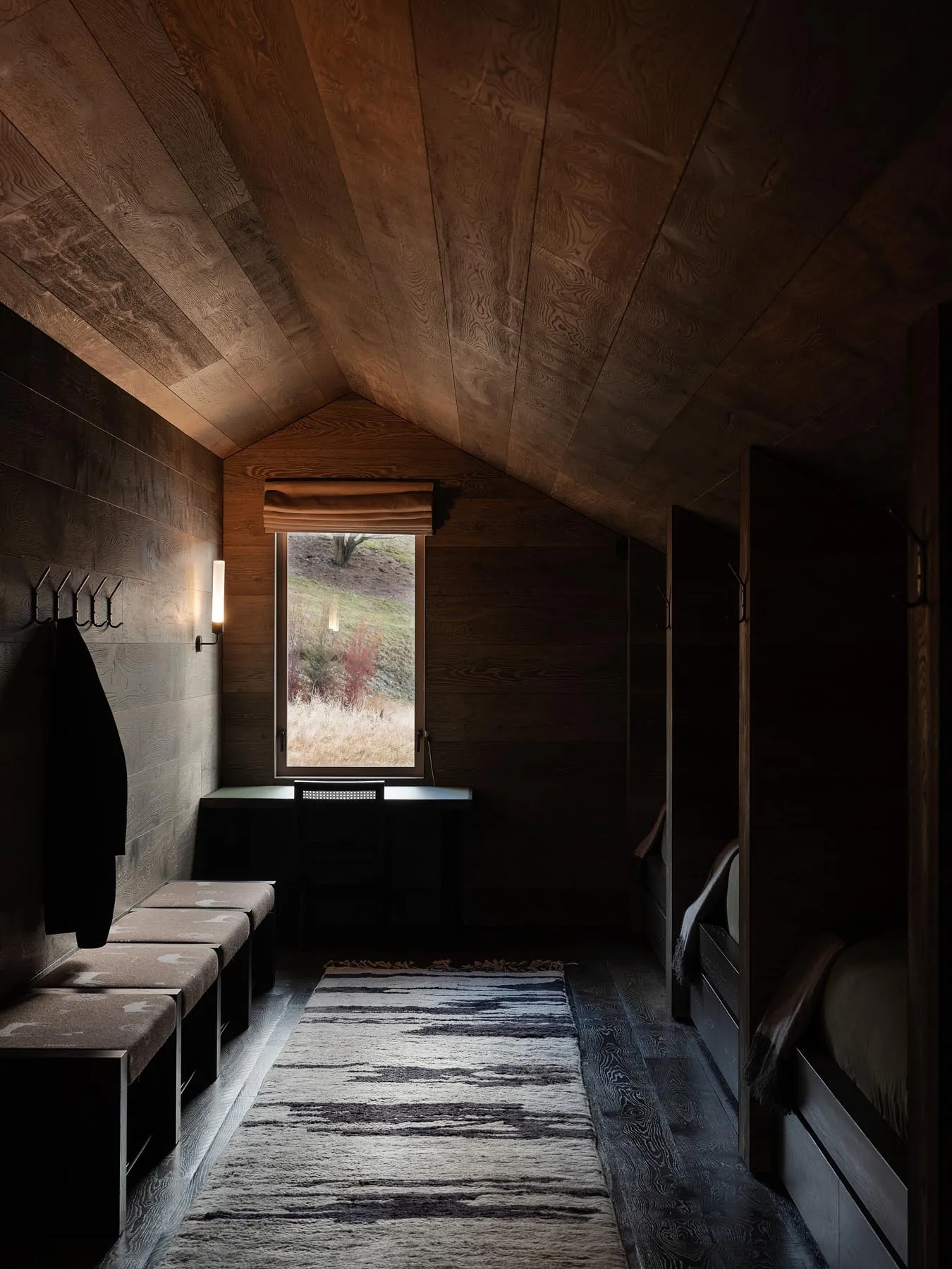 Modern minimalist bedroom with wood paneling, a window with natural light, and a cozy sitting area.