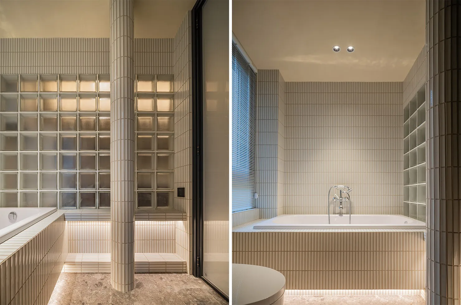 Modern bathroom with white ceramic tiles, glass block wall, and freestanding bathtub.