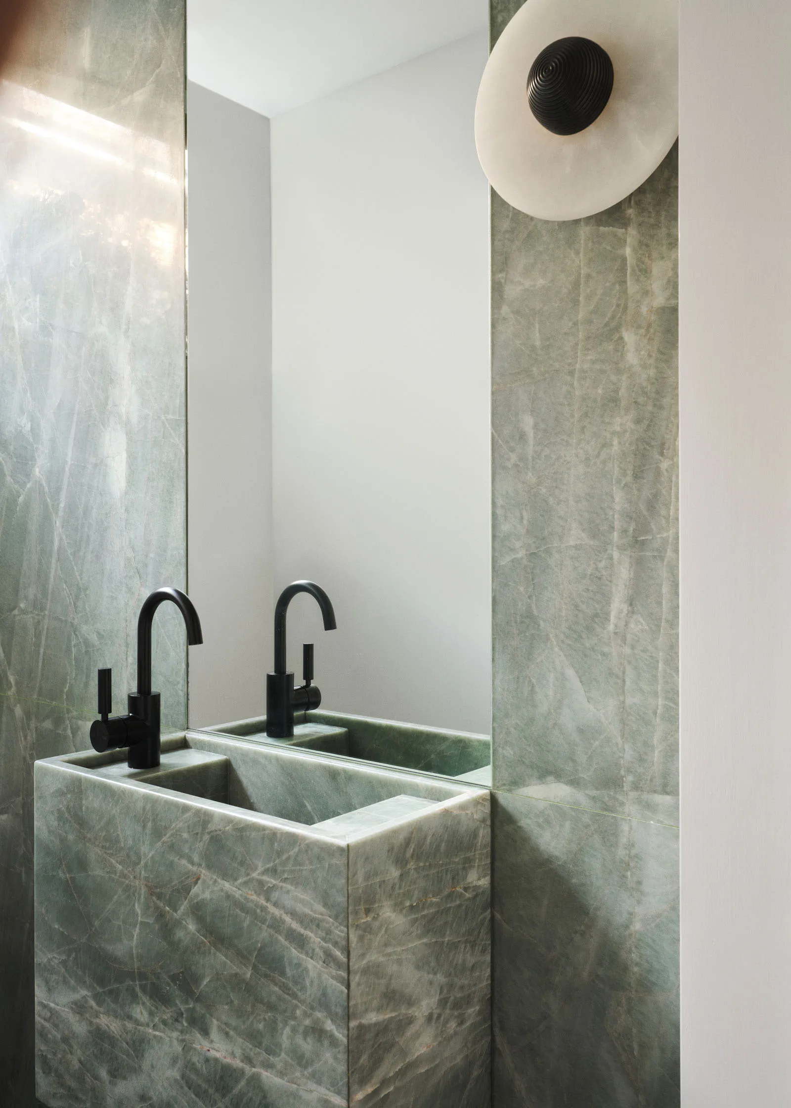 Modern bathroom with marble sink and faucets, black hardware, and a large mirror.