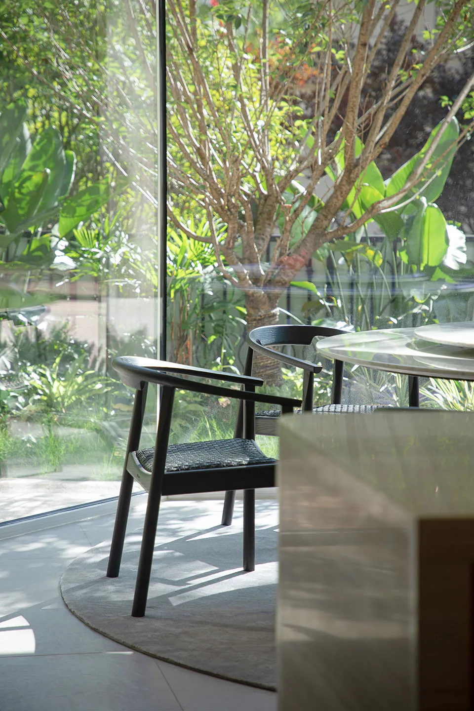 Modern home office interior with wooden furniture and large windows showcasing greenery outside.