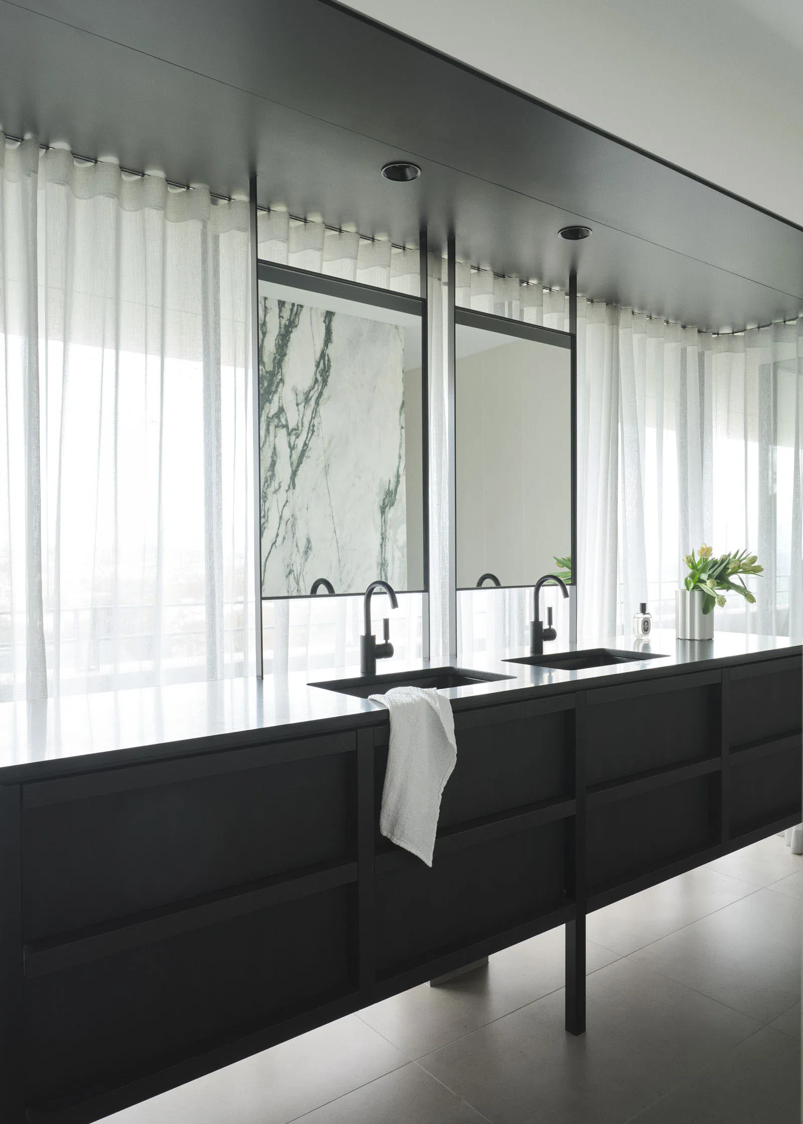 Modern, minimalist bathroom featuring a marble countertop with black fixtures.