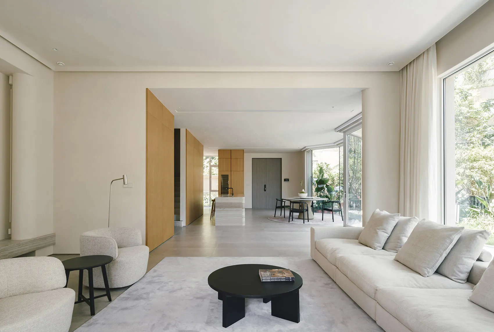 Modern, minimalist living room with concrete flooring, white furniture, and large windows.