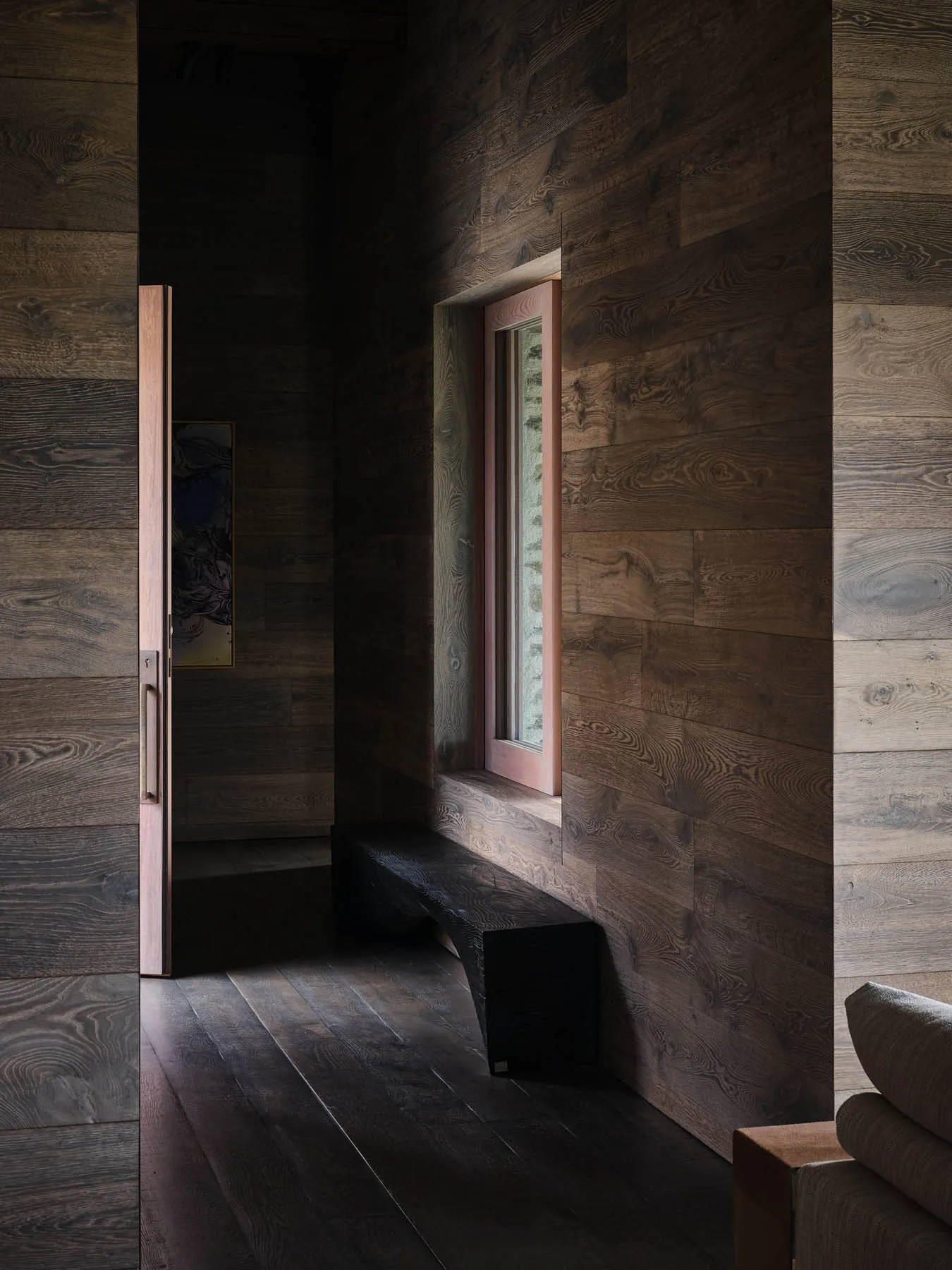 A modern residential interior with wooden walls and a window allowing natural light to enter.