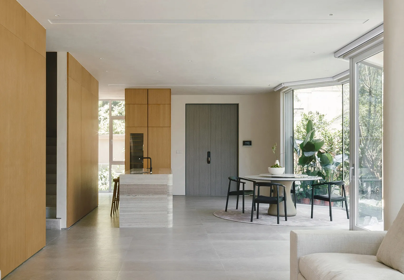 A modern residential living space featuring a kitchen island with marble countertops, a dining area with a round table and ch