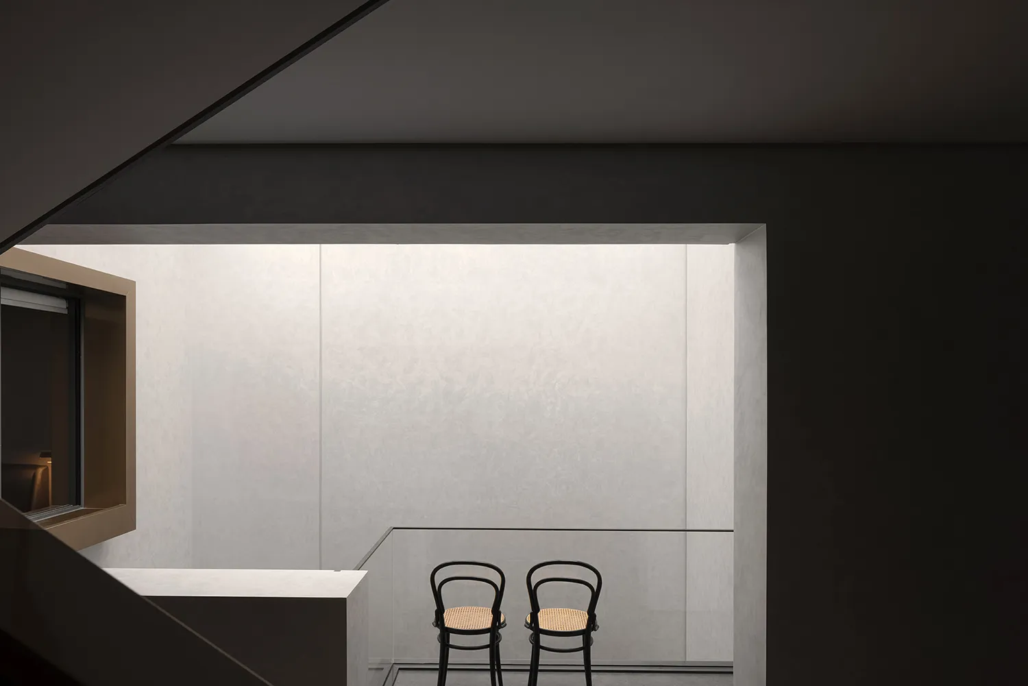 Two minimalist chairs in a modern, minimalist concrete interior space.