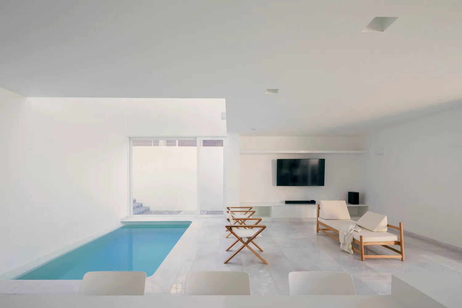 Contemporary living space featuring a modern, minimalist design with white marble floors and a private pool area.