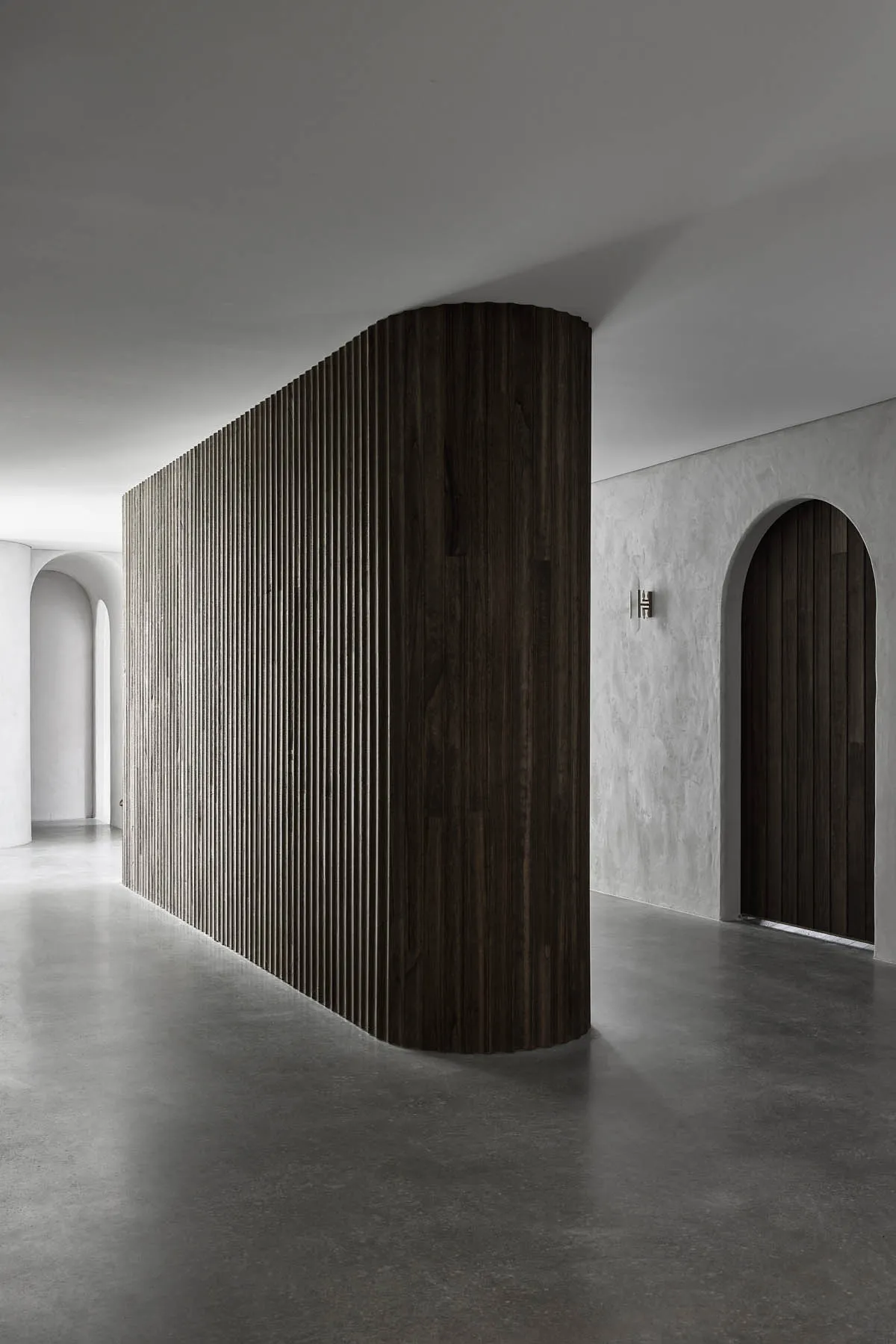 A sleek, modern minimalist interior featuring dark wood and concrete materials.