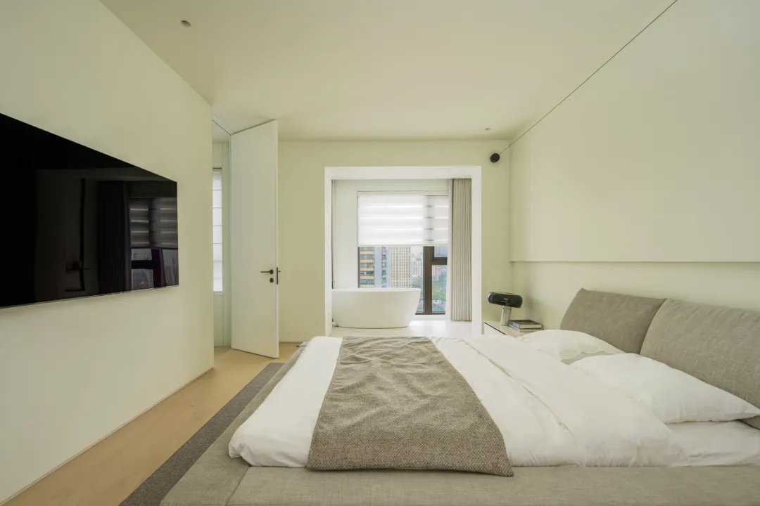 Modern minimalist bedroom featuring a bed with a fabric headboard, wooden floor, and glass window