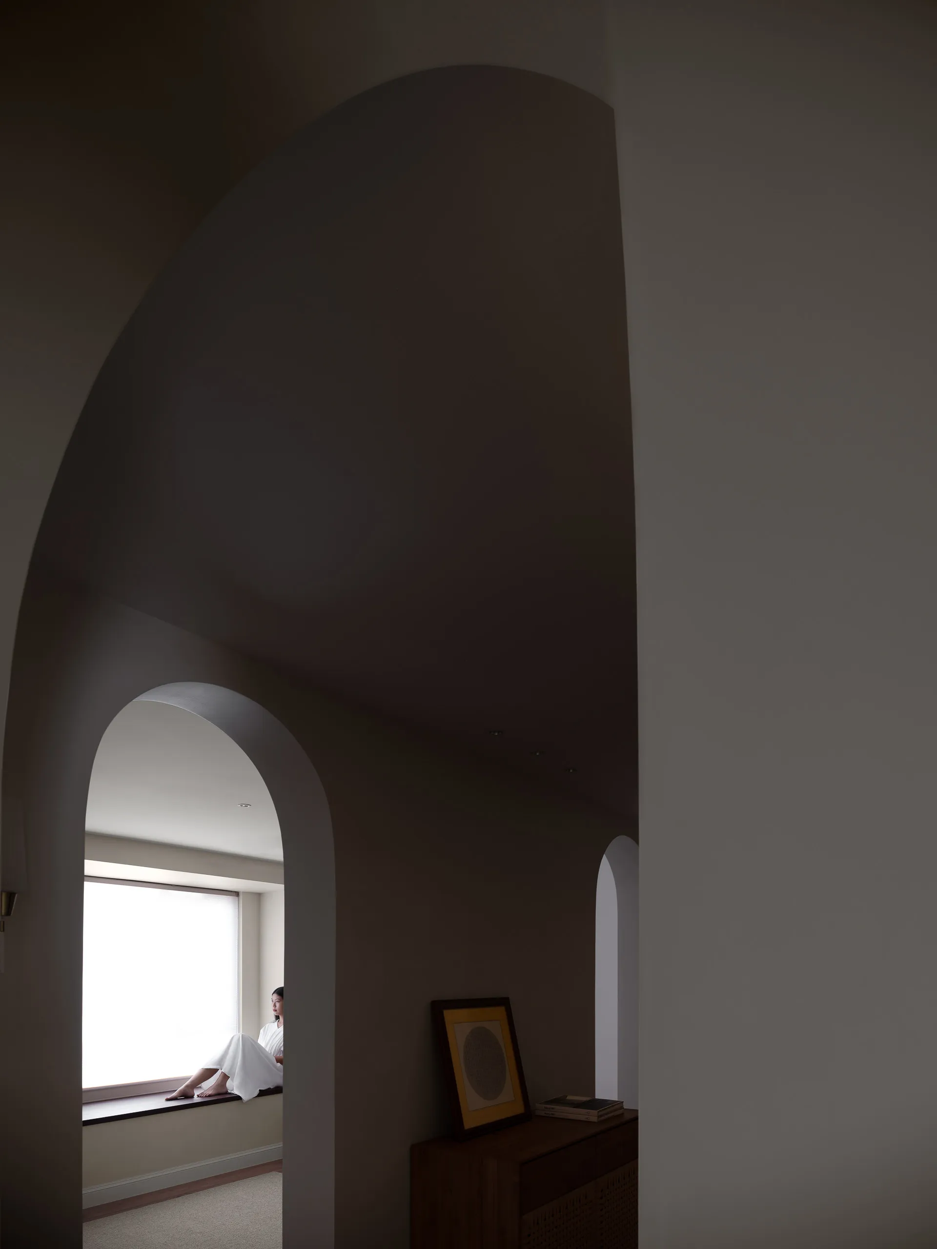 A minimalist interior space with concrete walls and a large window.