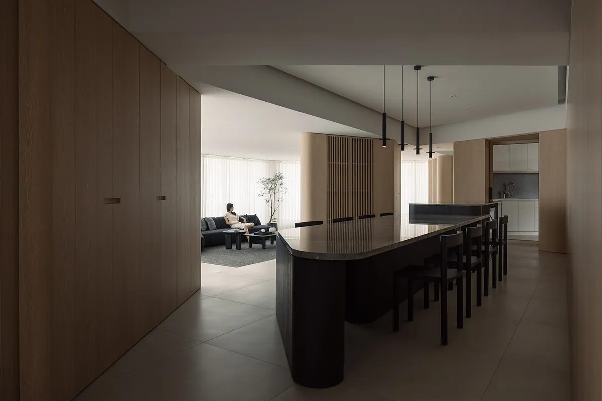 A modern, minimalist residential kitchen with a black island and wooden cabinetry.