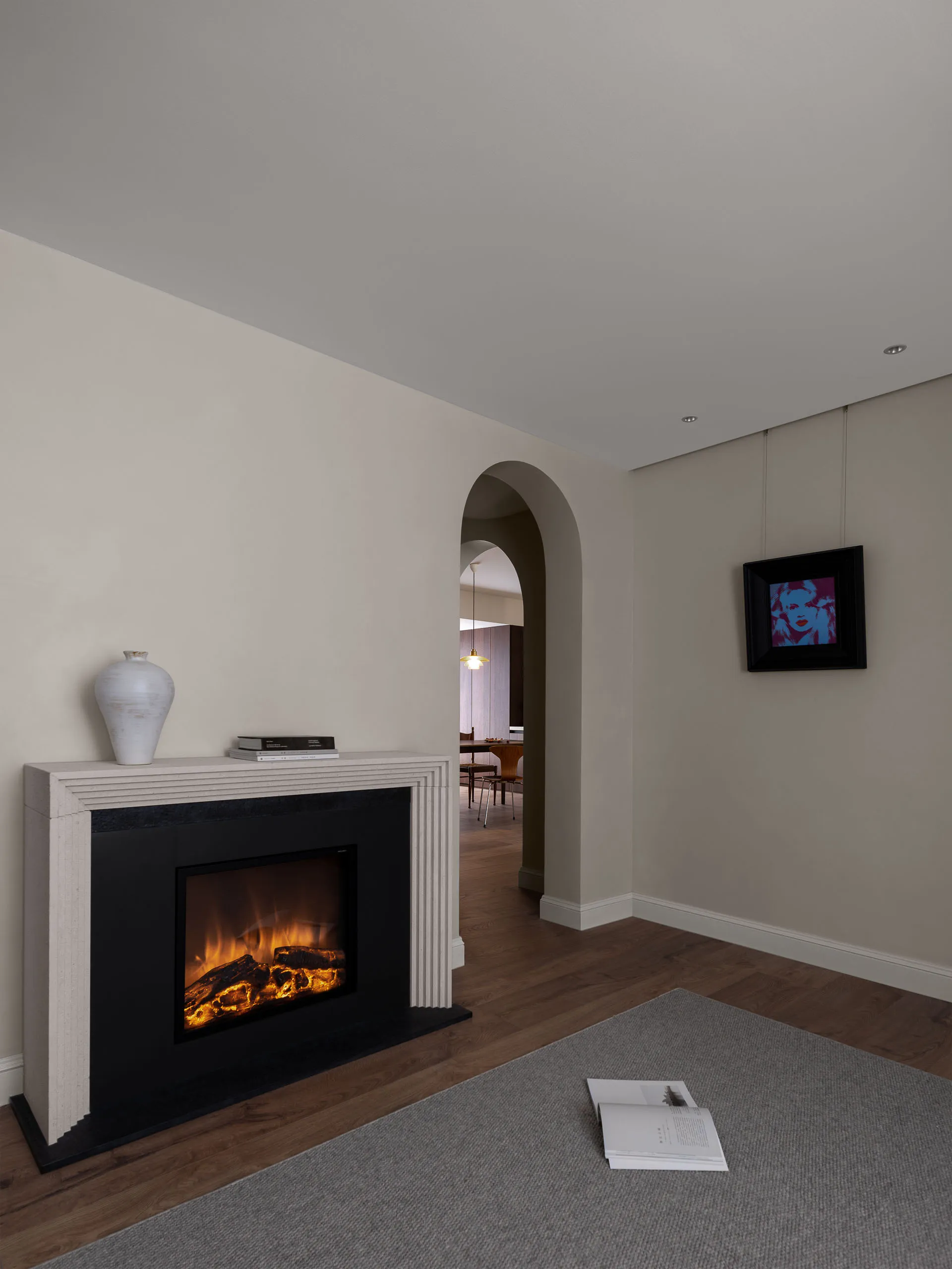 Modern interior living room with a concrete fireplace and arched doorway.