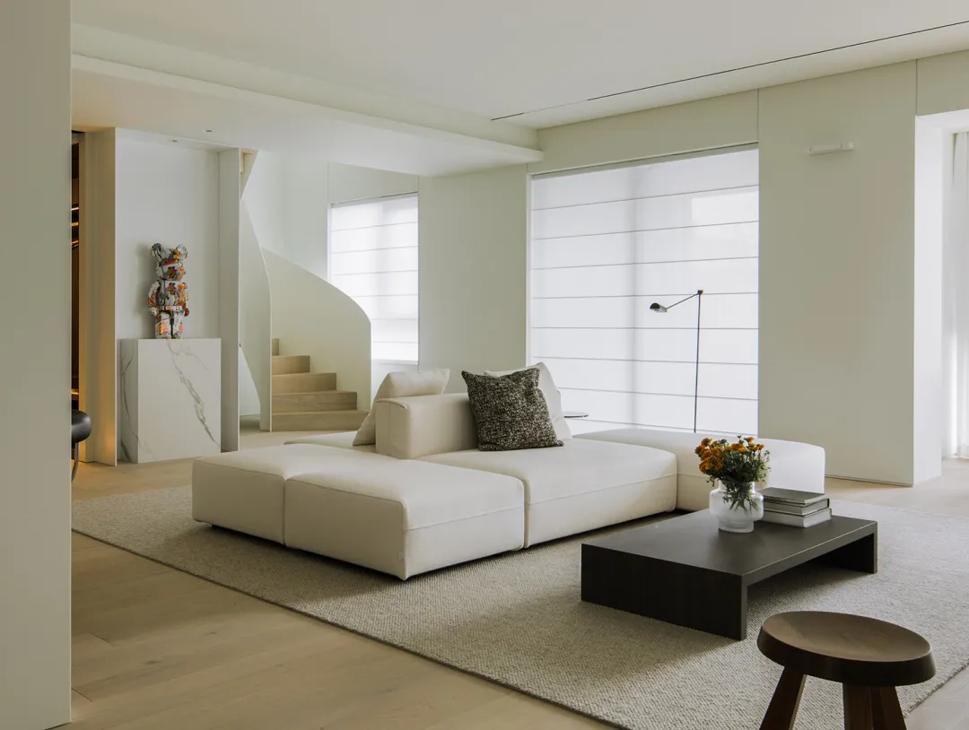 A modern living room featuring clean, neutral-colored furniture and minimalist decor.