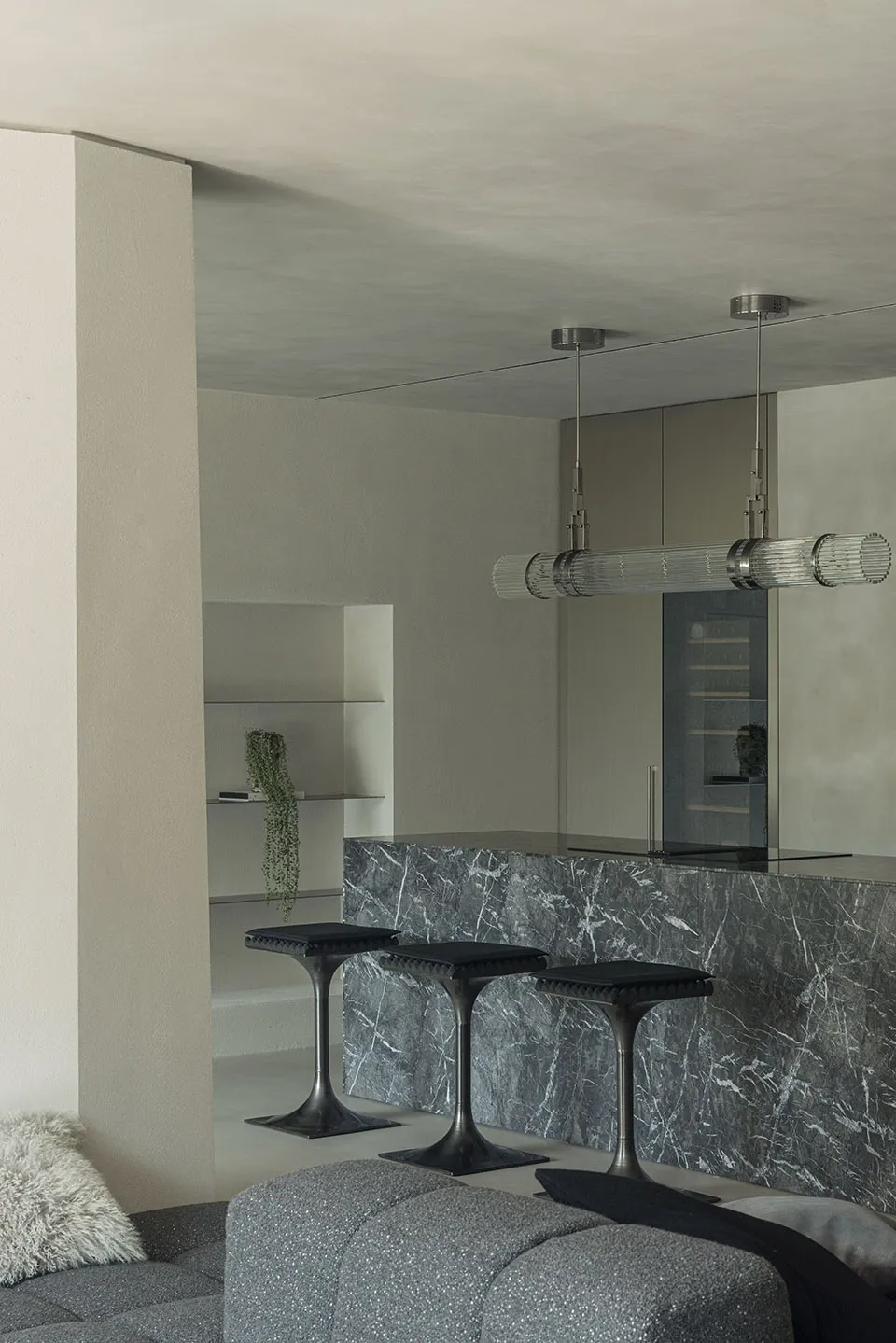 A modern living room with a marble counter and sleek, black stools.