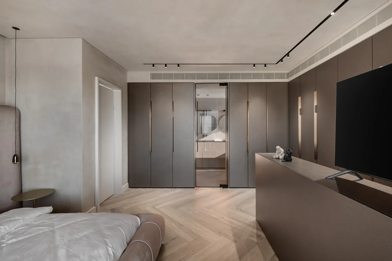 A modern minimalist bedroom with a large bed, wooden flooring, and metallic accents.