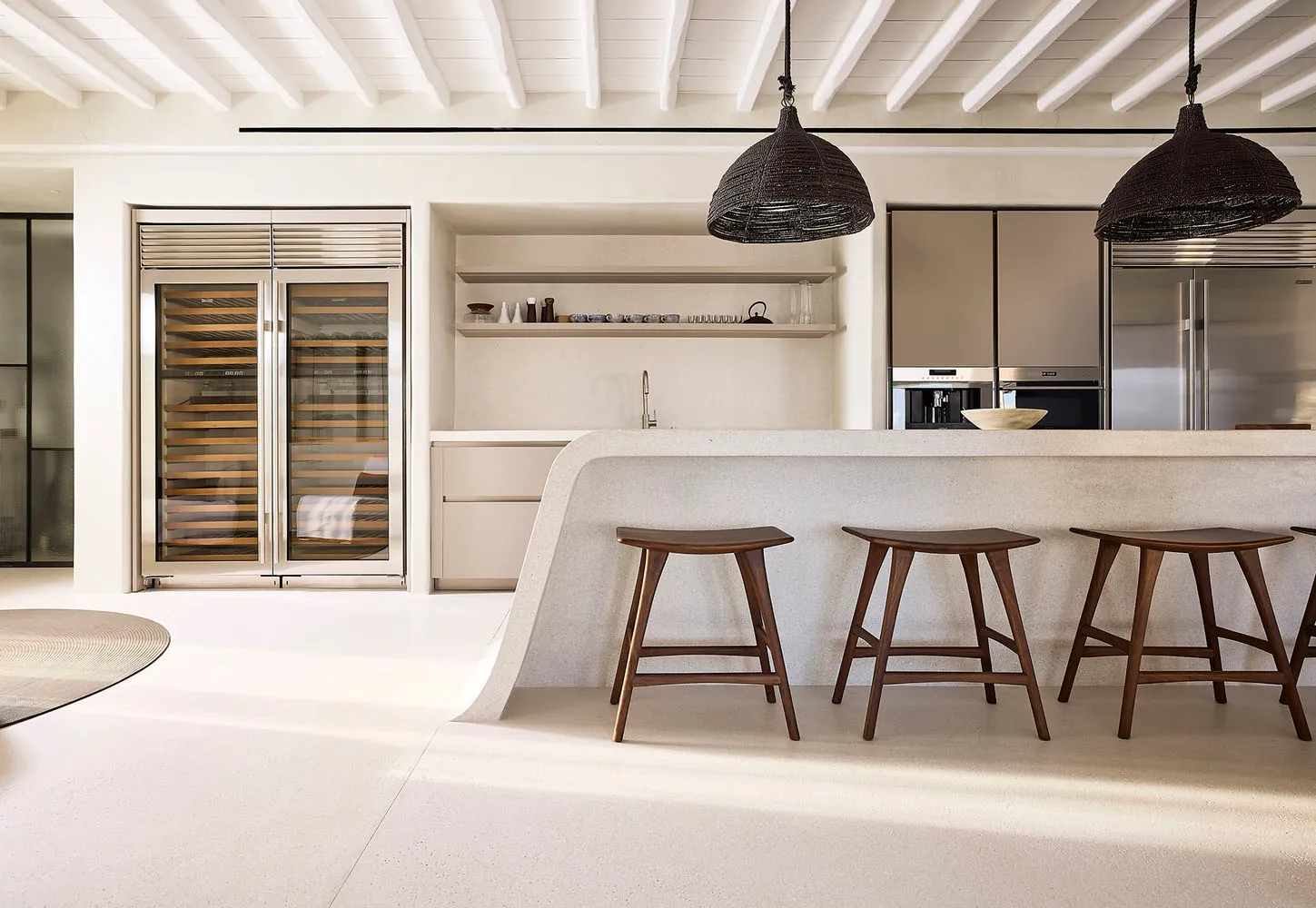Modern minimalist kitchen featuring terrazzo countertops and wooden bar stools.