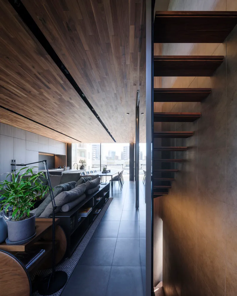 Modern, minimalist living room with wooden flooring and concrete walls.