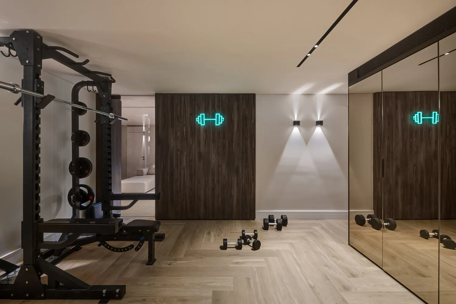 A modern home workout space featuring a range of exercise equipment and dumbbells on the floor, surrounded by wooden flooring