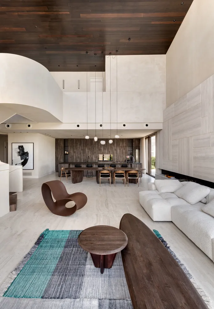 Modern living room with white furniture, a wooden coffee table, and a blue, gray, and white rug.