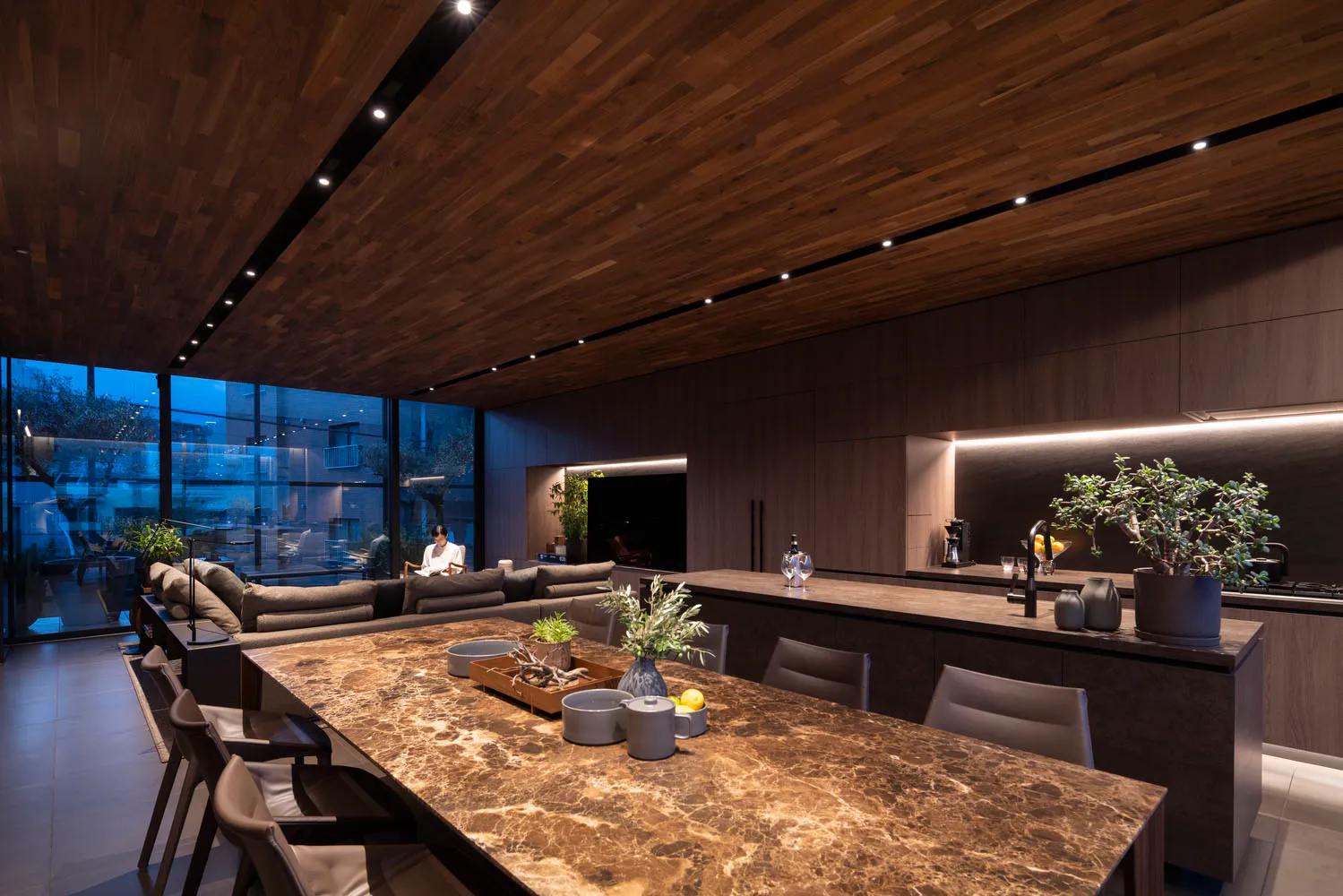 Modern residential kitchen with marble countertops, dark wood ceiling, and built-in lighting.