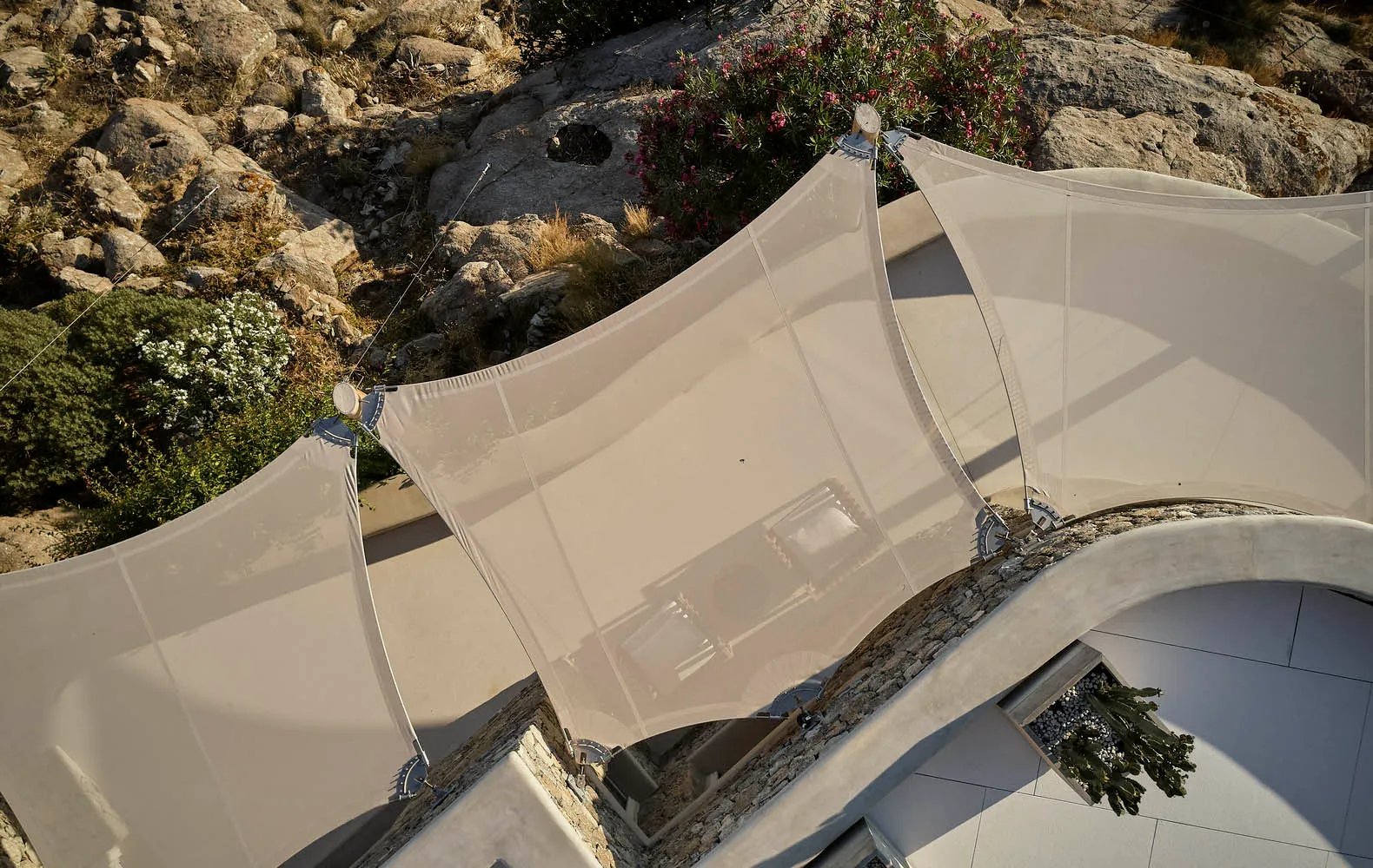 A rooftop patio covered with a fabric canopy, overlooking a rocky landscape.