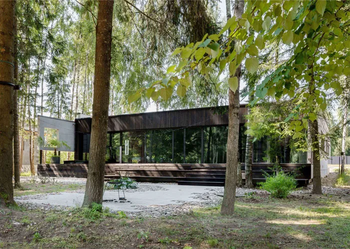 A modern house exterior made of wood, surrounded by trees.