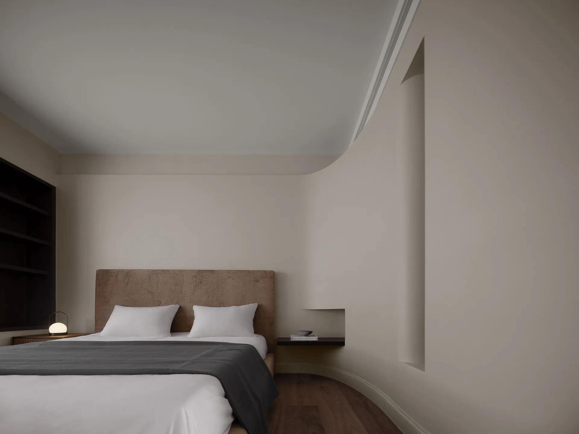 A modern minimalist bedroom with neutral-colored walls, bed, and bedding.
