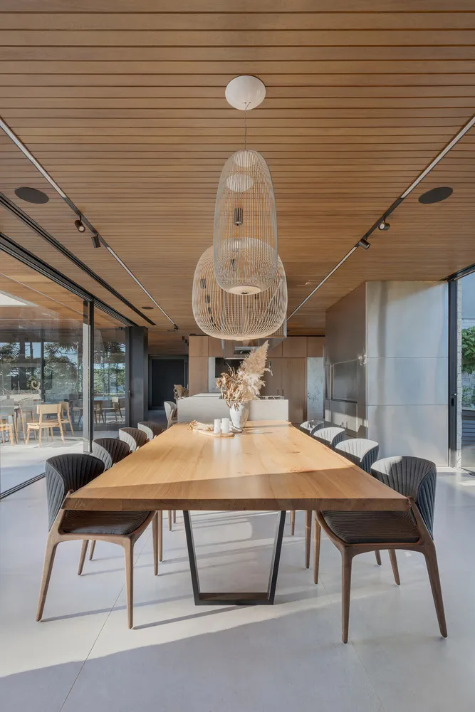 Modern dining room with a wooden table and chairs, featuring a minimalist design aesthetic.