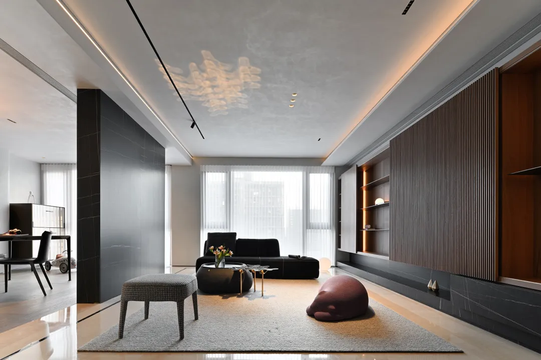 A modern living room with concrete walls, a black sofa, and a wooden coffee table.