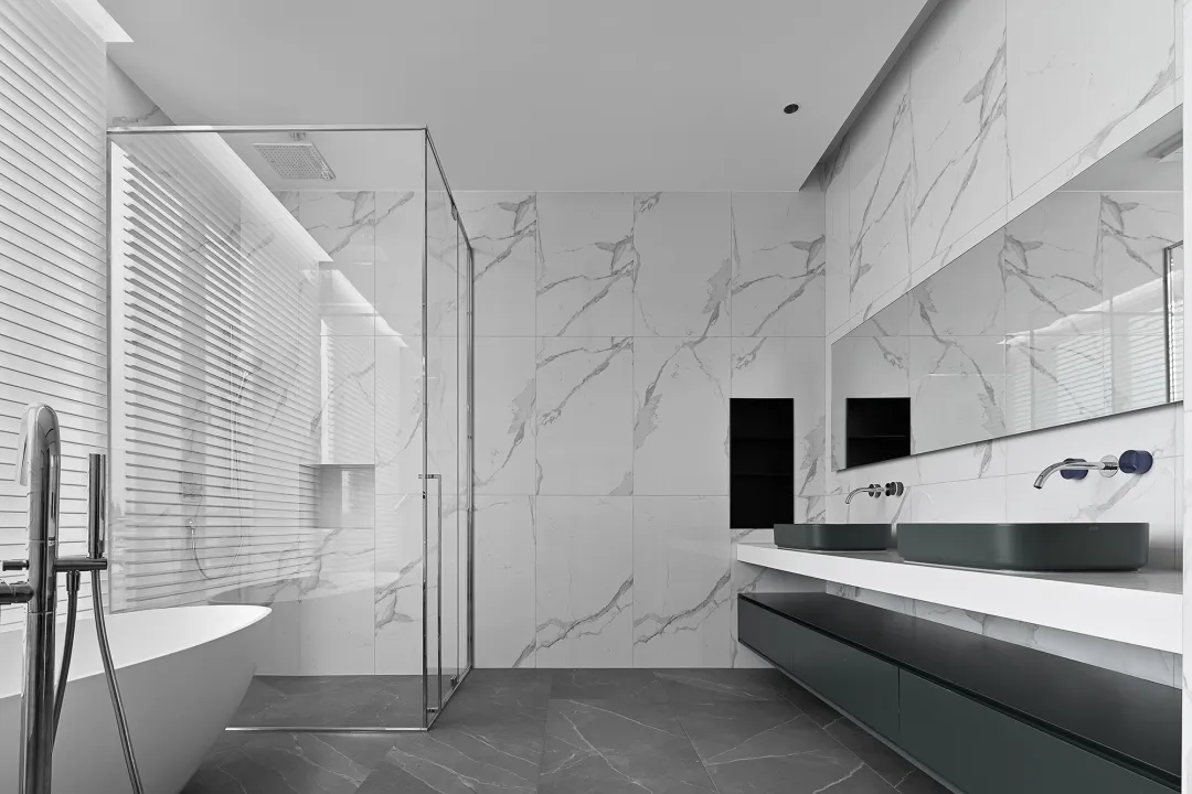 Modern minimalist bathroom with marble walls and floor, featuring a freestanding bathtub, a walk-in shower, and a floating va