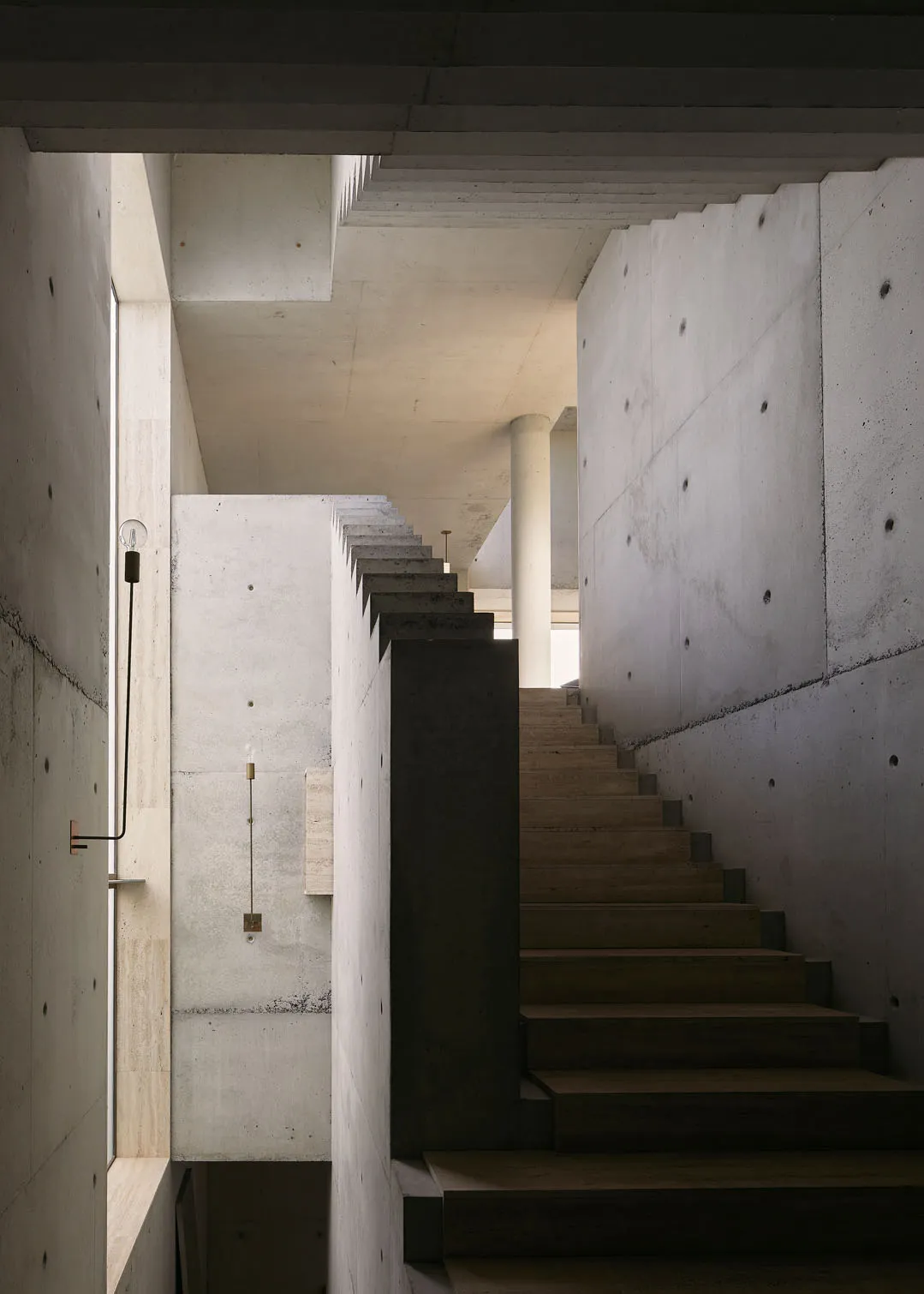 A modern interior featuring a monolithic staircase made of concrete.
