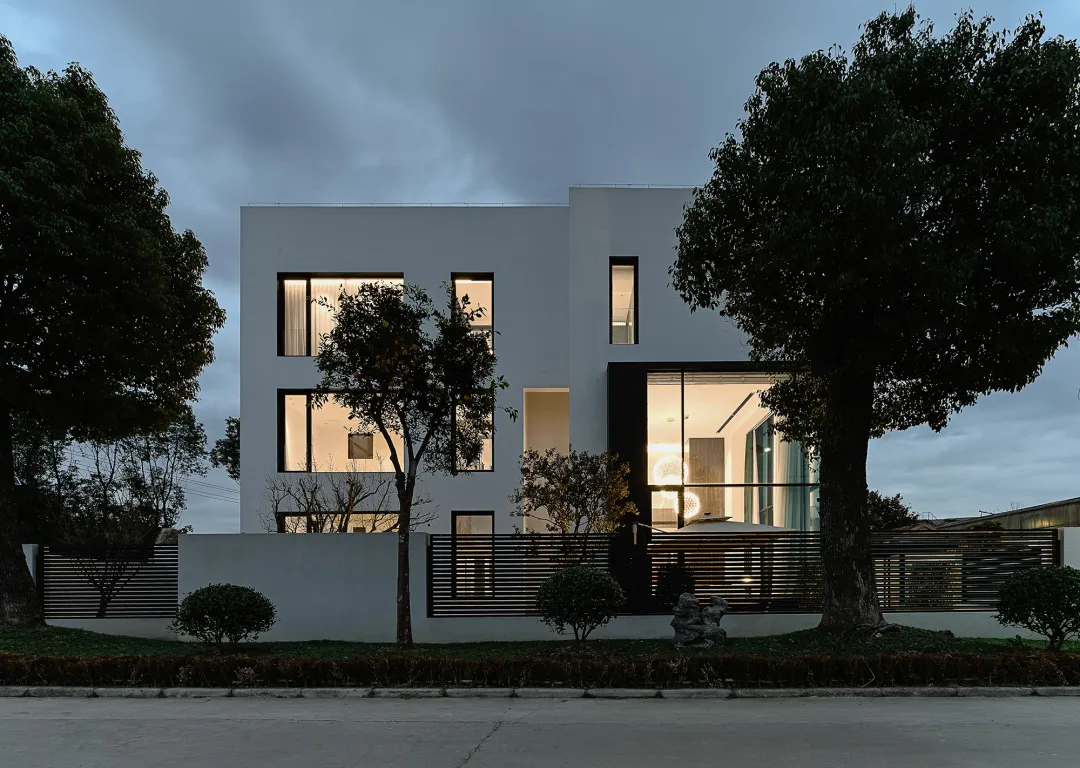 Modern residential exterior featuring a sleek, minimalist design with large windows and concrete finishing.
