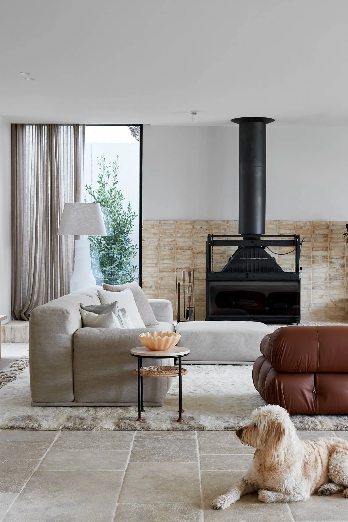 A minimalist living room featuring a grey sofa, modern fireplace, and wooden flooring.