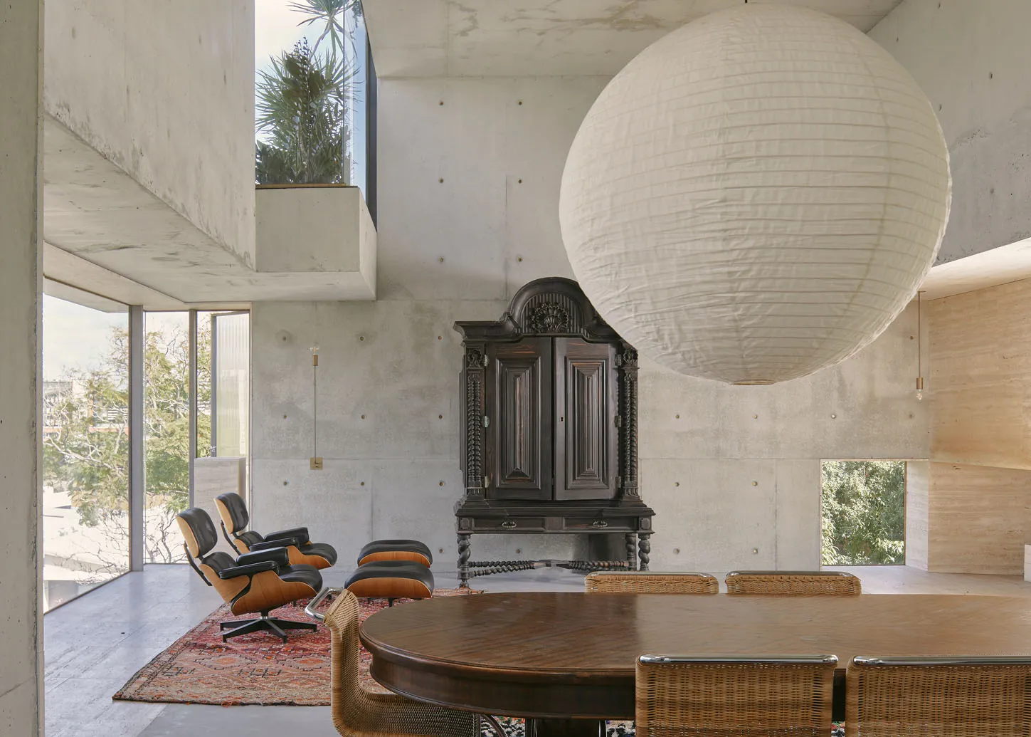 A modern living room with concrete walls, a large spherical pendant light, and minimalist furniture.