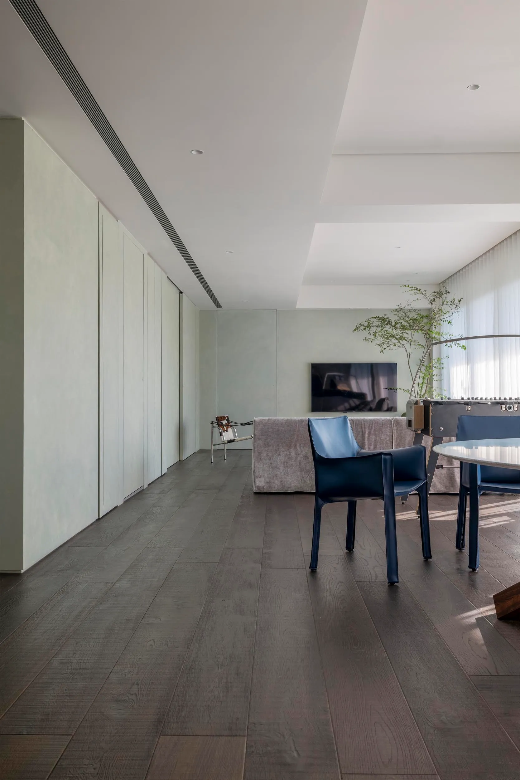 Contemporary living room featuring wood flooring and minimalist furniture.