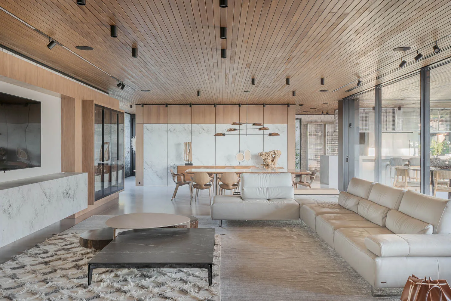 A modern living room with wooden ceiling, marble walls, and a leather sofa.