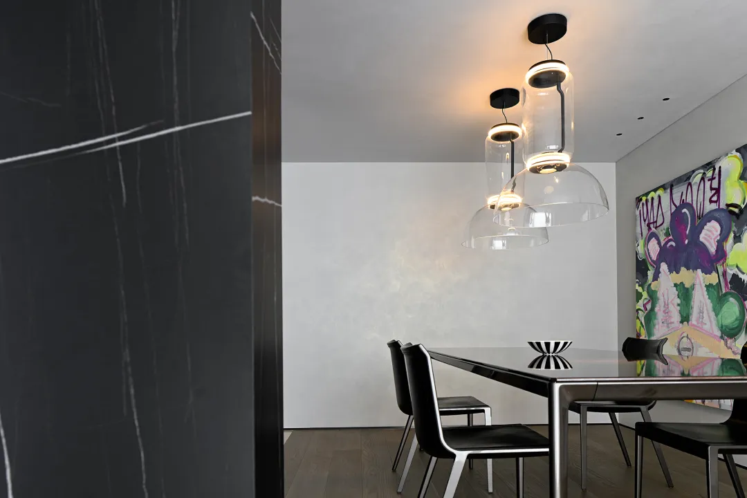 Modern minimalist dining room with black glass table and contemporary black chairs.