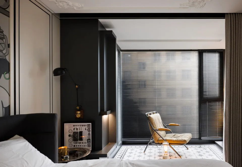 A modern bedroom featuring black accent walls and a comfortable seating area by the window.