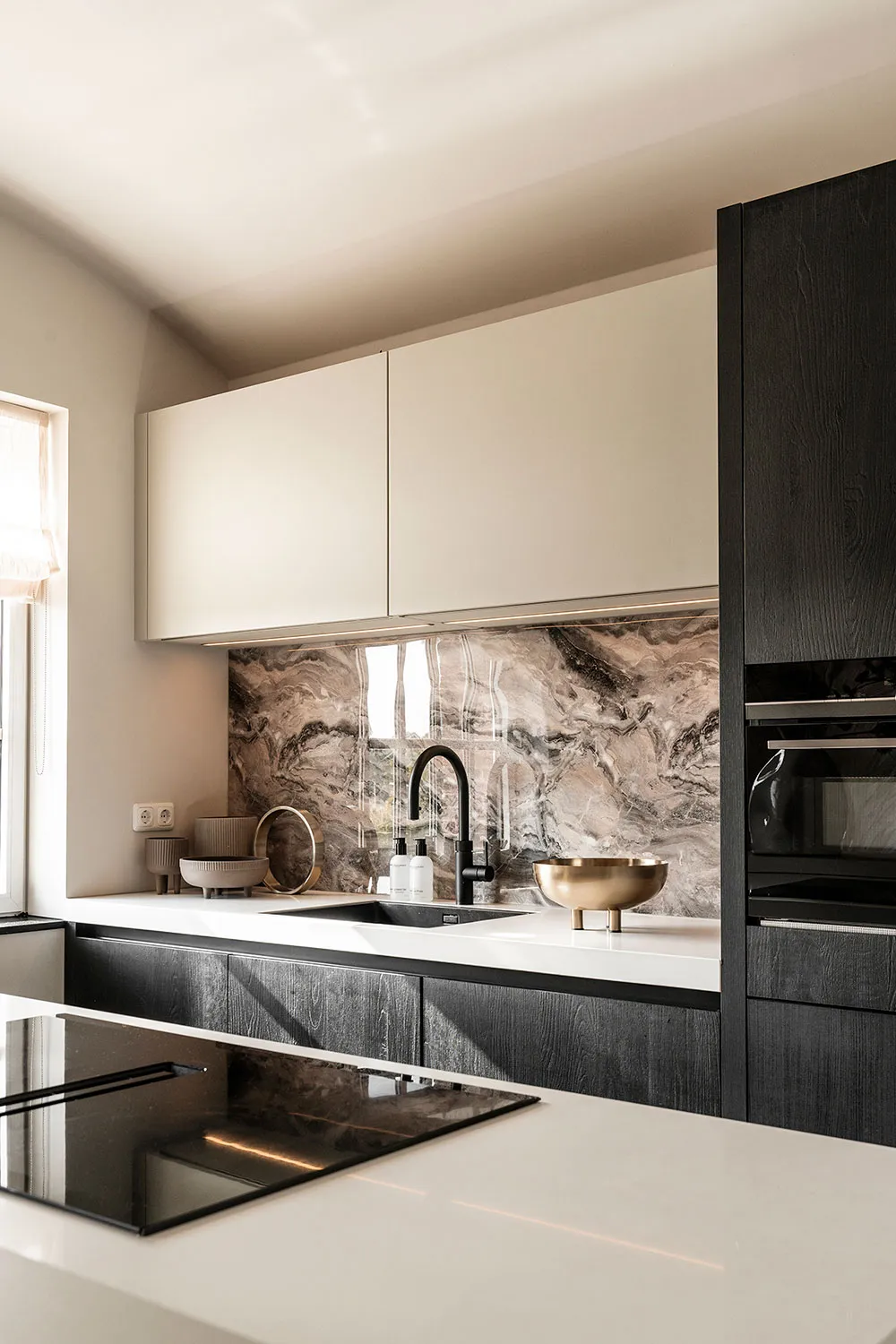 Modern residential kitchen featuring marble countertops and backsplash.