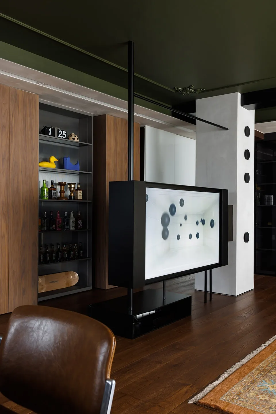 A modern living room featuring wooden walls and floor with a media console, a large screen displaying abstract art, and a lea