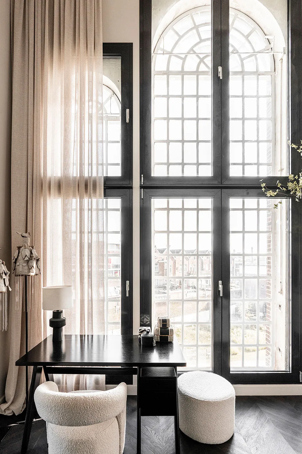 Modern minimalist home office space with a wooden table, white chair, and sheer curtains.
