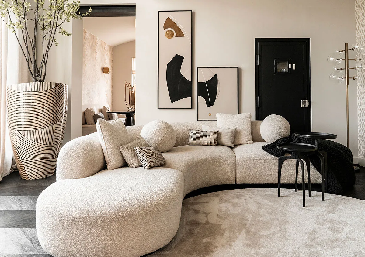 A modern, simple sofa with white velvet upholstery and spherical cushions in a living room setting.