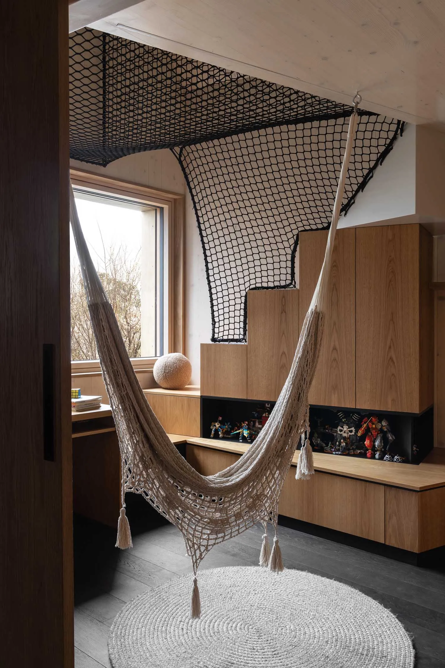 An industrial-style home office with a hammock suspended from the ceiling, featuring wood materials and a cozy workspace.