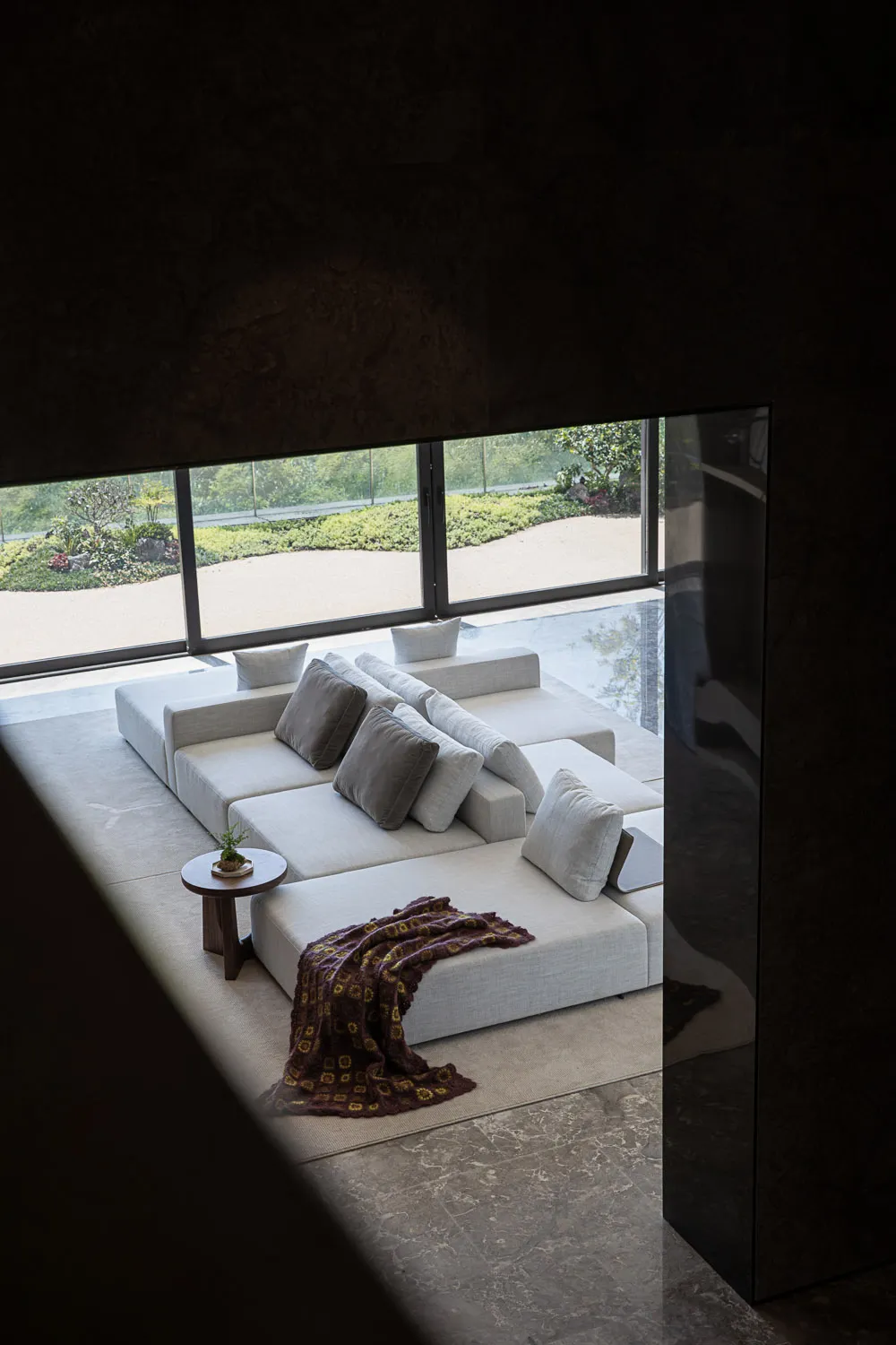 A minimalist living room with a concrete wall, fabric lounge seating, and a small wooden side table.