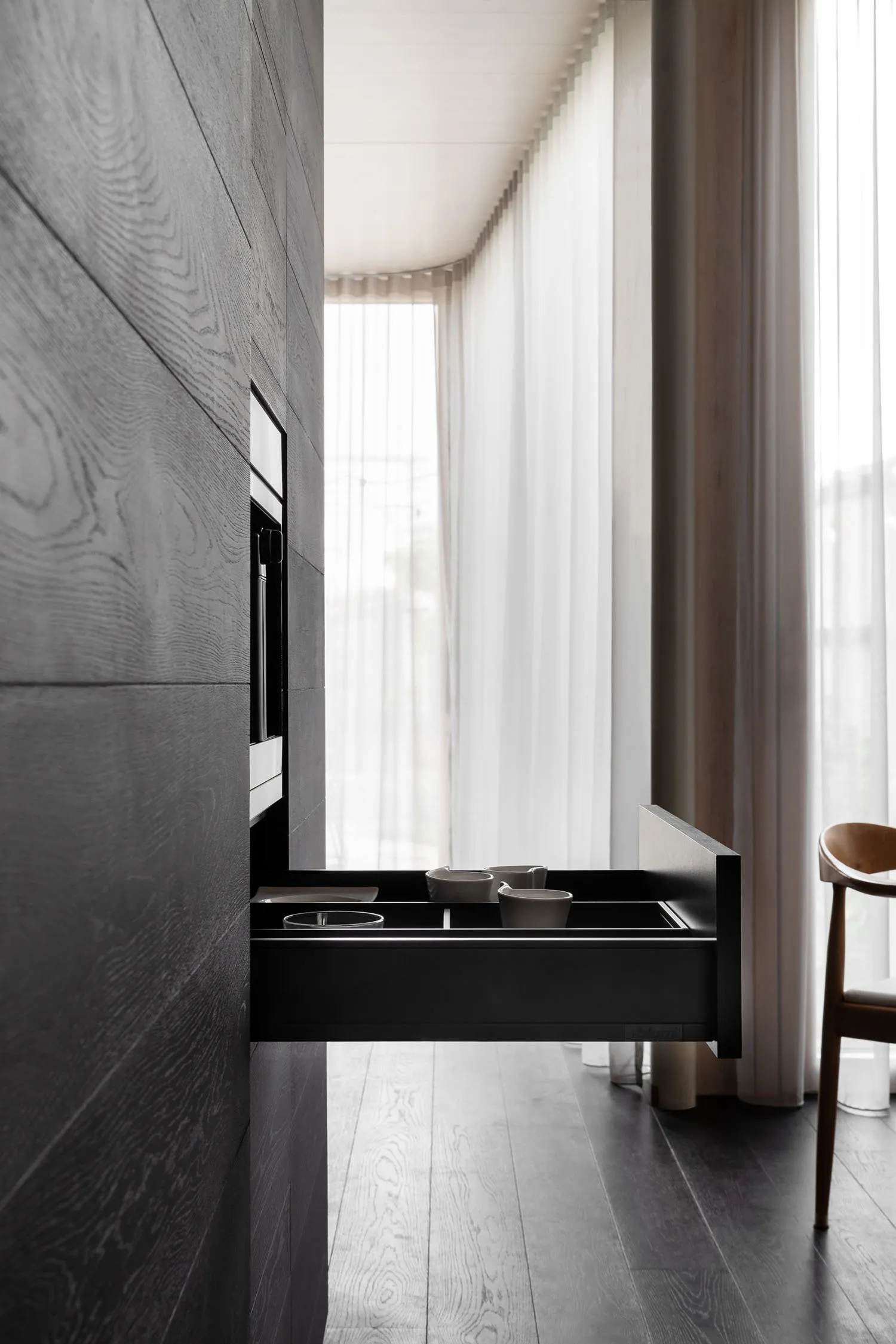 Modern black kitchen cabinets with wooden elements and white counter.