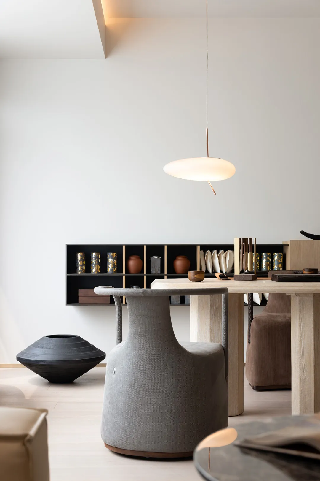 Modern interior design featuring a wooden dining table with taupe upholstered chairs and minimalist decor.